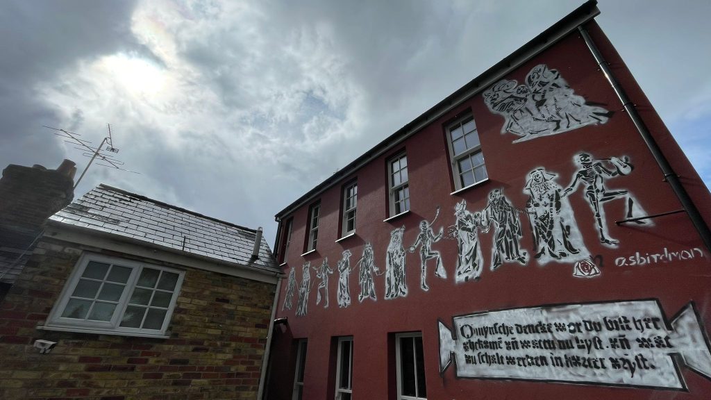 red wall of a house with black-and-white sprayed images on it