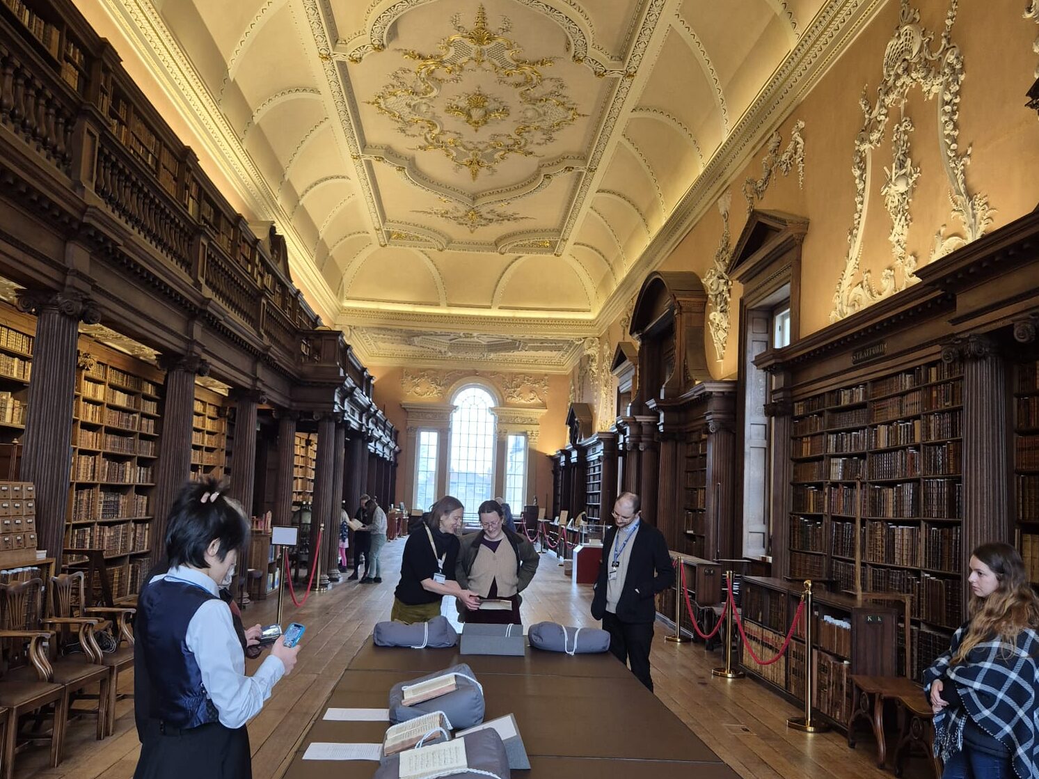 An exhibition of newly acquired Hebrew books laid out on centered table in the old Library with richly decorated ceiling of Christ Church College