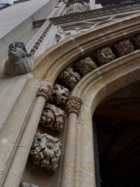 A photo of an entry arch at Merton College, showing a gargoyle and several ornaments from below. 